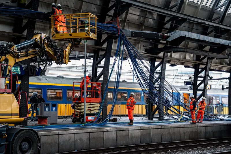 Monteurs trekken kabels op een stationsperron