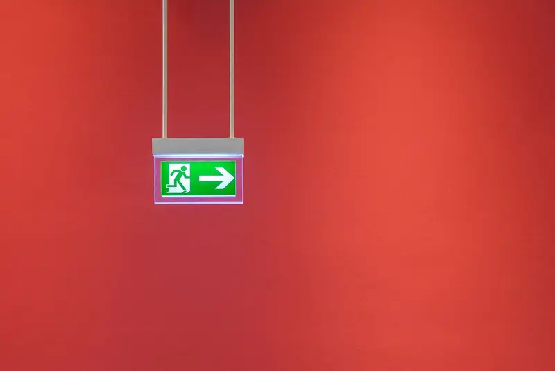 Groen vluchtwegbord aan een rode wand